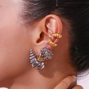Close-up of model wearing gold textured ear cuffs and silver shell star earrings set