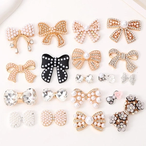 Flat lay macro of diverse bow hair accessories with pearls and rhinestones on beige surface
