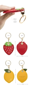Detail of strawberry and lemon leather keychains with gold clasps and brand engraving