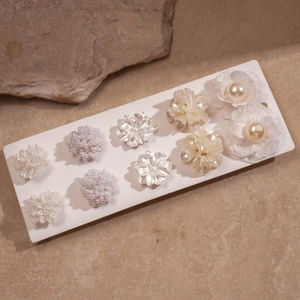 5-pair set of elegant white floral stud earrings with pearls on natural stone background