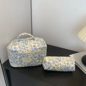 Close-up of blue floral quilted makeup bag and matching pouch on a dark surface