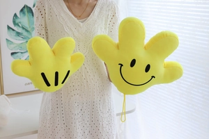 Detail of yellow plush cartoon palm pillow with smiley face and stripe design on a sofa