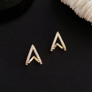 Exquisite gold V-shaped geometric stud earrings with diamonds on a black textured background