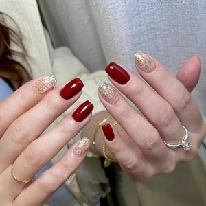 Short square press-on nails with deep red glossy finish and champagne gold glitter accents
