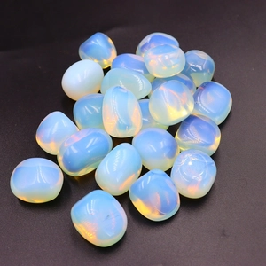 Macro shot of polished iridescent opalite tumbled stones on a textured black background