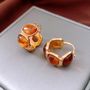 Macro shot of amber resin square hoop earrings with gold trim on jewelry box