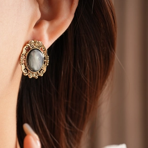 Close-up of vintage golden hollow-carved oval resin earrings on a female model