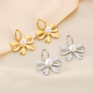 French vintage bow pearl earrings in gold and silver finish on soft beige satin