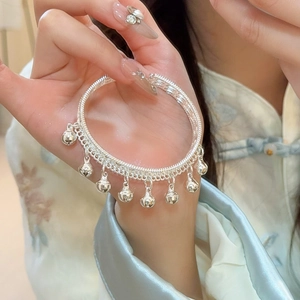 Détail d'un bracelet à clochettes argenté avec texture tissée porté sur un mannequin