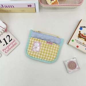 Macro detail of quilted stripe coin purse with cute bear patch on desktop setting