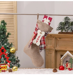 Linen Christmas stocking with red plaid cuff and bone-shaped JOY tag hanging by a fireplace