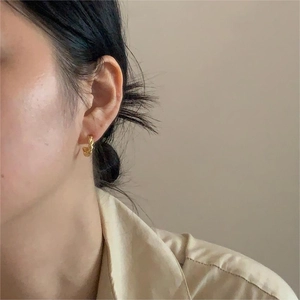 Close-up of minimalist gold twisted rope hoop earrings worn on a model's ear