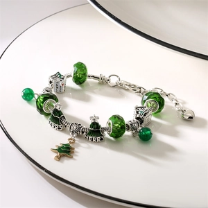 Christmas charm bracelet with green beads, snowman and tree charms on a ceramic plate