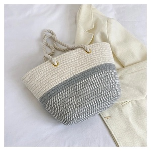 Detailed top view of handmade woven tote bag with thick rope handles on white bedding