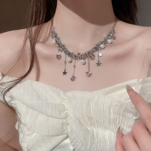 Détail du collier argenté multicouche avec breloques papillon, étoile et pompon perle