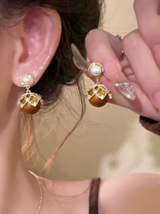 Detailed close-up of 18K gold plated drop earrings with brown beads and small pearls