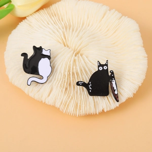 Cute black and white cat enamel pins featuring a spooky cat with a knife on orange background