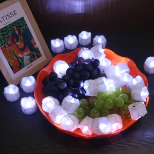 Detail of petal-shaped LED flameless candles glowing inside an orange fruit bowl