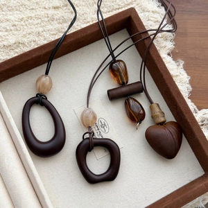 Three vintage wood and resin geometric pendant necklaces displayed on a linen tray
