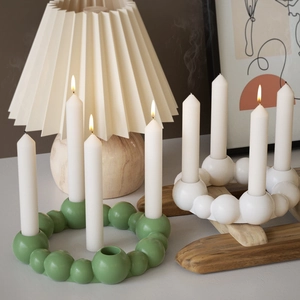 Detailed view of bubble bead candle holders in green and white resin with lit candles