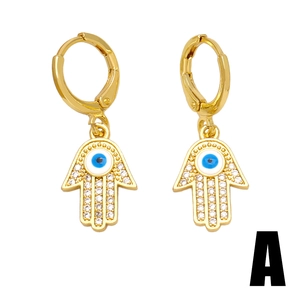 Boucles d'oreilles main de Fatma dorées avec œil bleu et zircons sur fond blanc