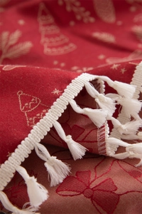 Close-up of red Christmas tablecloth featuring white fringe tassels and jacquard fabric texture