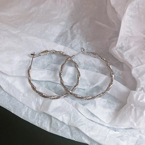 Detail of silver twisted geometric hoop earrings with textured woven metal design