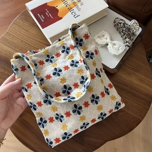 Detailed embroidery on vintage canvas tote bag with floral patterns on a wooden table