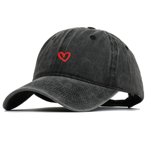 Dettaglio del ricamo a cuore rosso su cotone nero lavato di un cappellino vintage