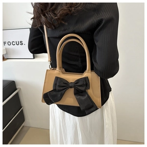 Crossbody view of a stylish bow-knot handbag with a contrast brown and black design