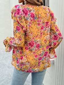 Detail view of pink floral pattern on yellow long-sleeve shirt with ruffle shoulder design