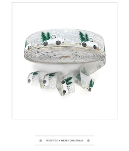 Detail of silver Christmas ribbon with white truck and green tree patterns for gift wrapping