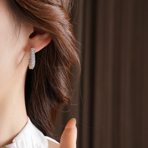 Gros plan d'une boucle d'oreille carrée en argent et zircone portée par un mannequin