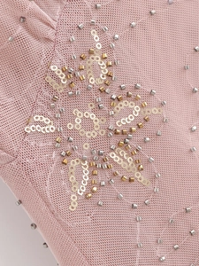 Macro detail of pink knit mesh fabric with intricate gold sequins and silver bead stars