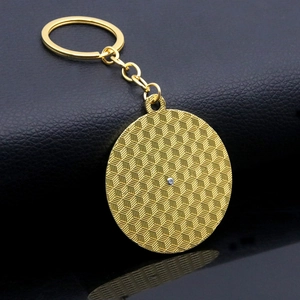 Detail of golden spinning mood keychain with 3D geometric texture on black leather