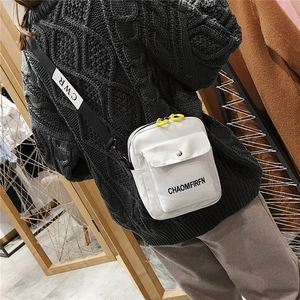 White canvas mini crossbody bag with black lettered strap and yellow zipper detail