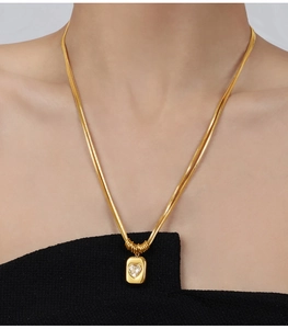 Close-up of gold plated layered snake chain necklace with heart stone square pendant