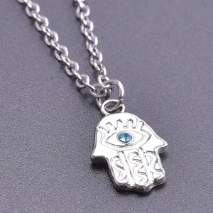Détail du pendentif Main de Fatma argenté avec pierre œil bleu sur socle sombre