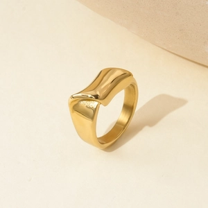 Detailed macro view of an irregular wave gold titanium steel ring on a beige background