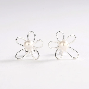 Macro view of silver flower stud earrings with elegant white pearl inlay detail
