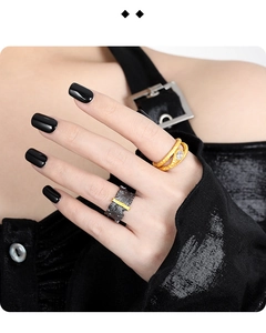 Detailed close-up of textured gold wavy ring with inset diamonds and black bar accent