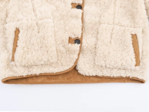 Detailed close-up of beige fleece jacket with brown suede piping and classic button closure
