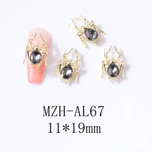 Macro detail of 3D spider nail charms with grey teardrop rhinestones on gold alloy base