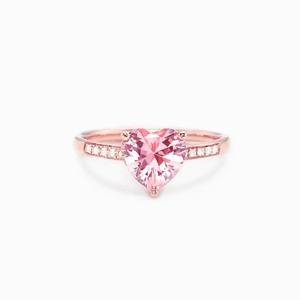 Detail of rose gold ring featuring a large pink heart gemstone and pavé side diamonds