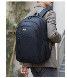 Side view of a black multi-compartment backpack worn by a person in an outdoor setting