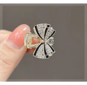 Close-up of elegant golden bow hair claw clip with black outlines and shiny rhinestones