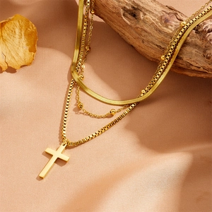 Three-layer gold stainless steel necklace with cross pendant on elegant satin background