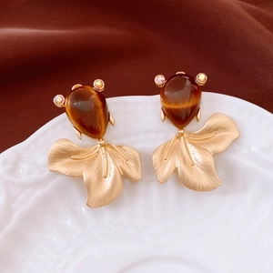 Detail of vintage goldfish earrings with brown gemstones and crystals on ceramic plate