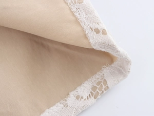 Detail shot of khaki fabric texture with white lace trimming on the skirt edge