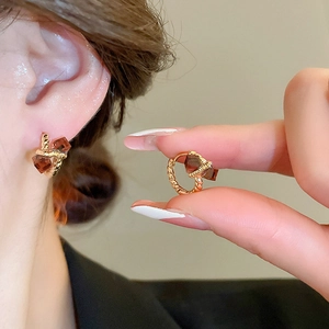 Detailed close-up of gold-plated twisted hoop earrings with brown square zircon stones